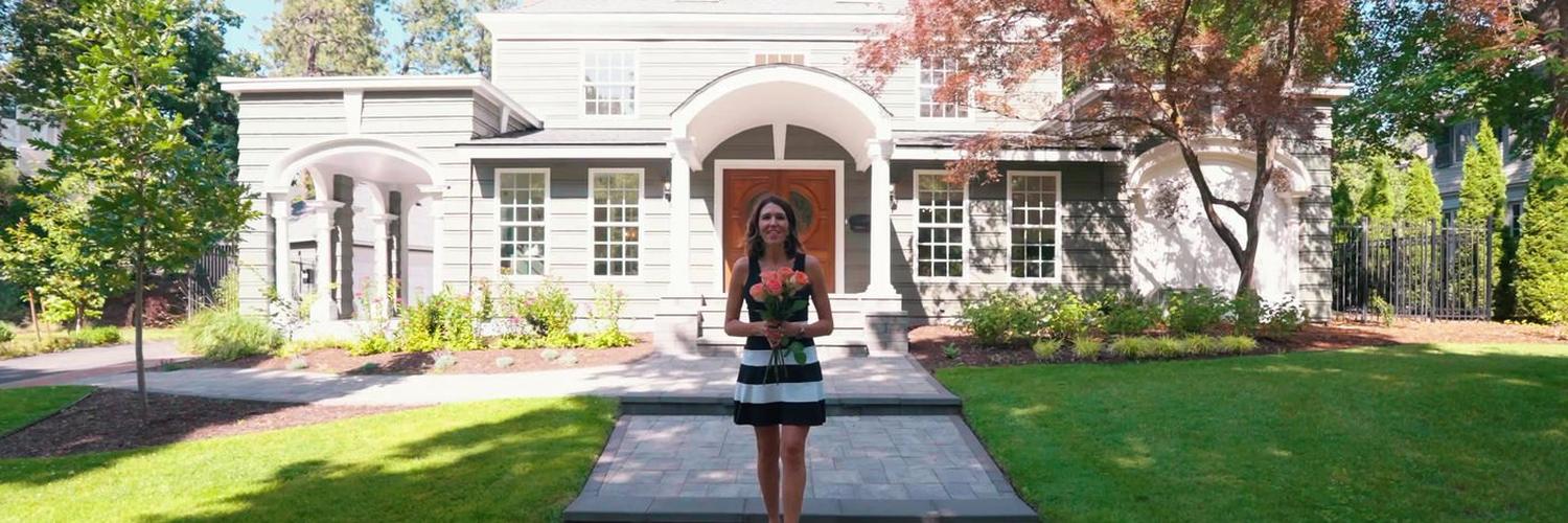 Agent walking the path to a large white luxury home.